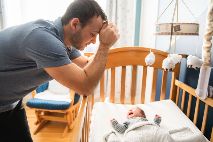 erschöpfter Vater mit Baby