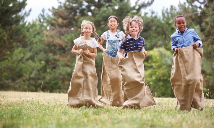 Kinder die beim Kindergeburtstag Sackhüpfen spielen