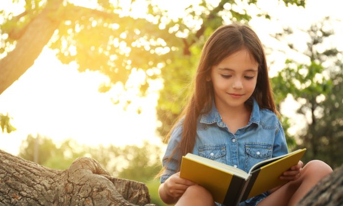 Kind das im Wald sitzt und liest